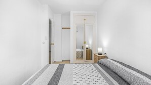 A bedroom with a bed, a nightstand, a mirror, and a door.
