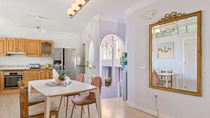 A modern kitchen with wooden cabinets, a dining table with chairs, and a large mirror on the wall.