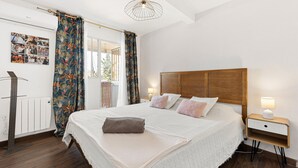 A neatly made bed with a wooden headboard, a bedside lamp, and a wall-mounted radiator.