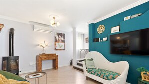 A living room with a sofa, a small table, a fireplace, and a TV mounted on the wall.