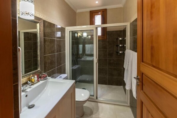 A bathroom with a bathtub, toilet, and a glass-enclosed shower area. - Hôtel Riad Airport Marrakech (Marrakech)