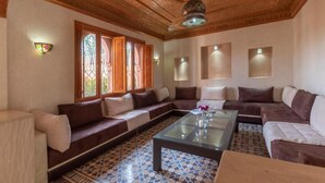 A living room with a patterned floor, a glass coffee table, and a ceiling with intricate woodwork. - Hôtel Riad Airport Marrakech (Marrakech)