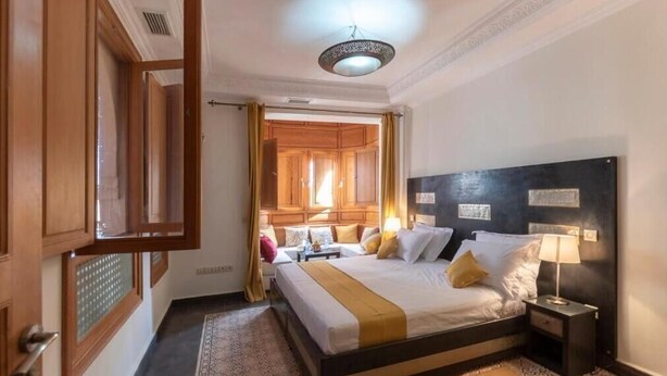 A hotel room with a bed, nightstands, a lamp, a mirror, and a door. - Hôtel Riad Airport Marrakech (Marrakech)