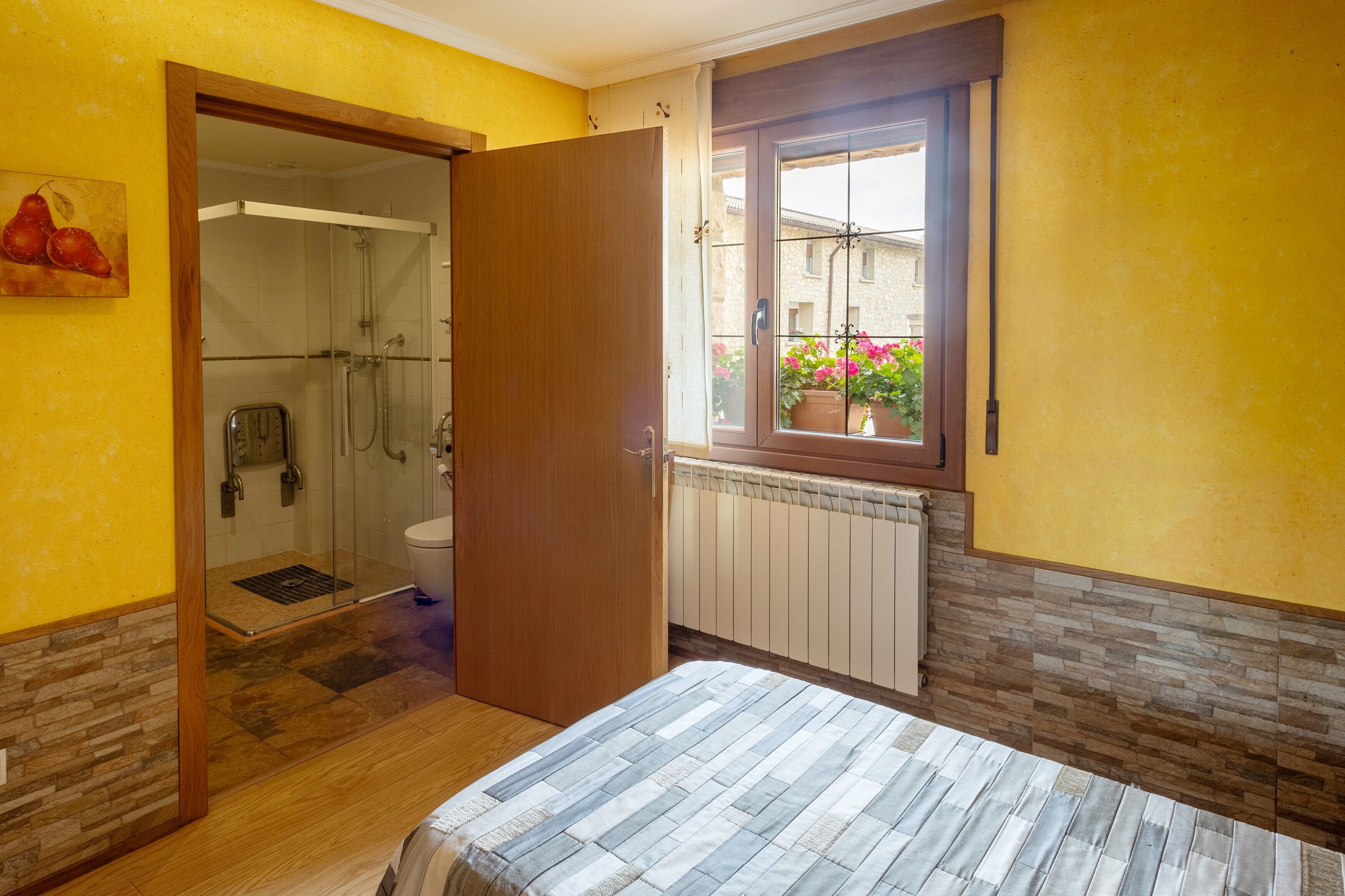 Een badkamer met een douche, toilet en een raam met uitzicht op een balkon.