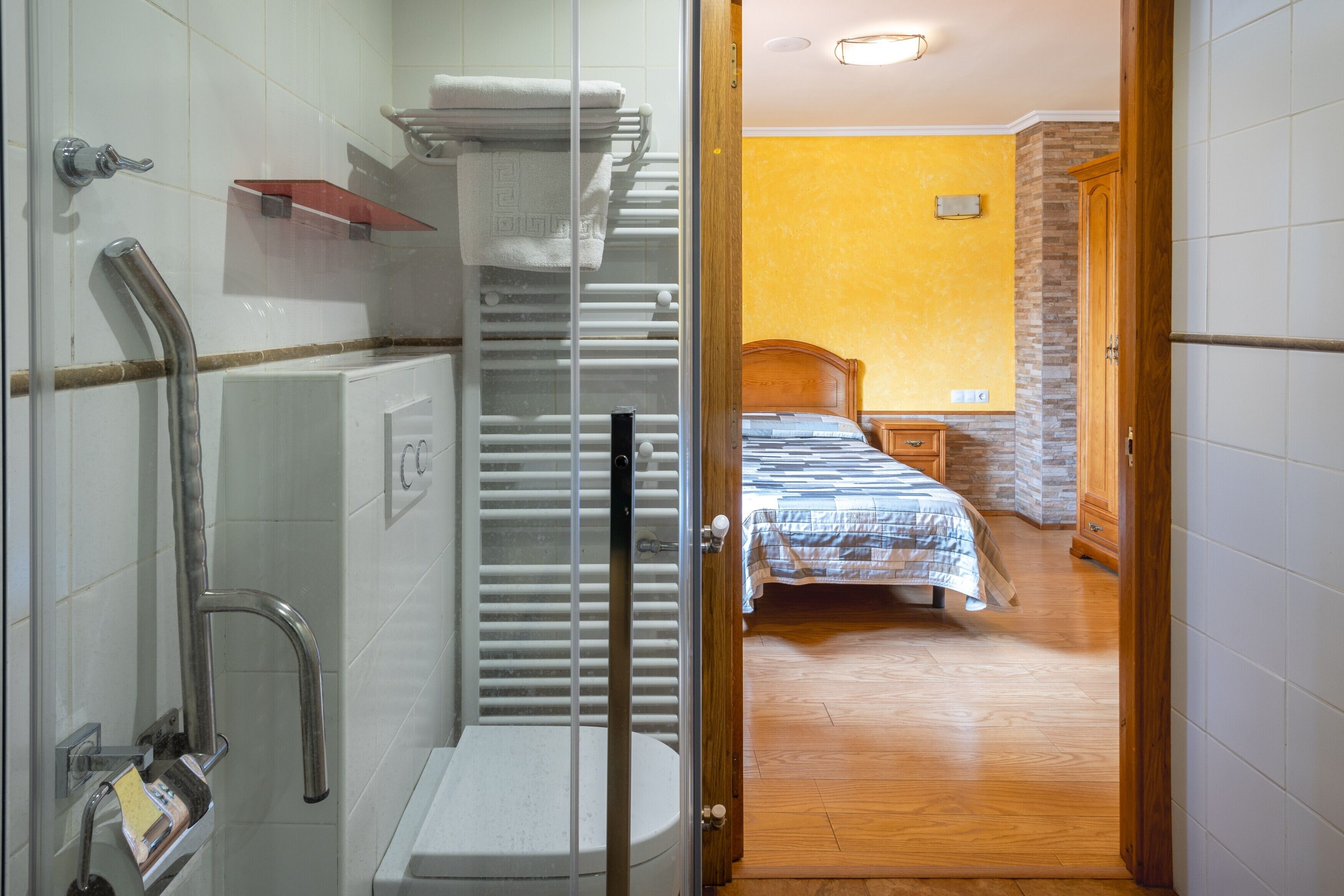 A bathroom with a shower, toilet, and towel rack.