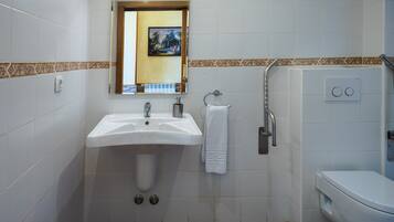 Une salle de bain équipée d’un lavabo, d’un miroir, d’un porte-serviettes et de toilettes.