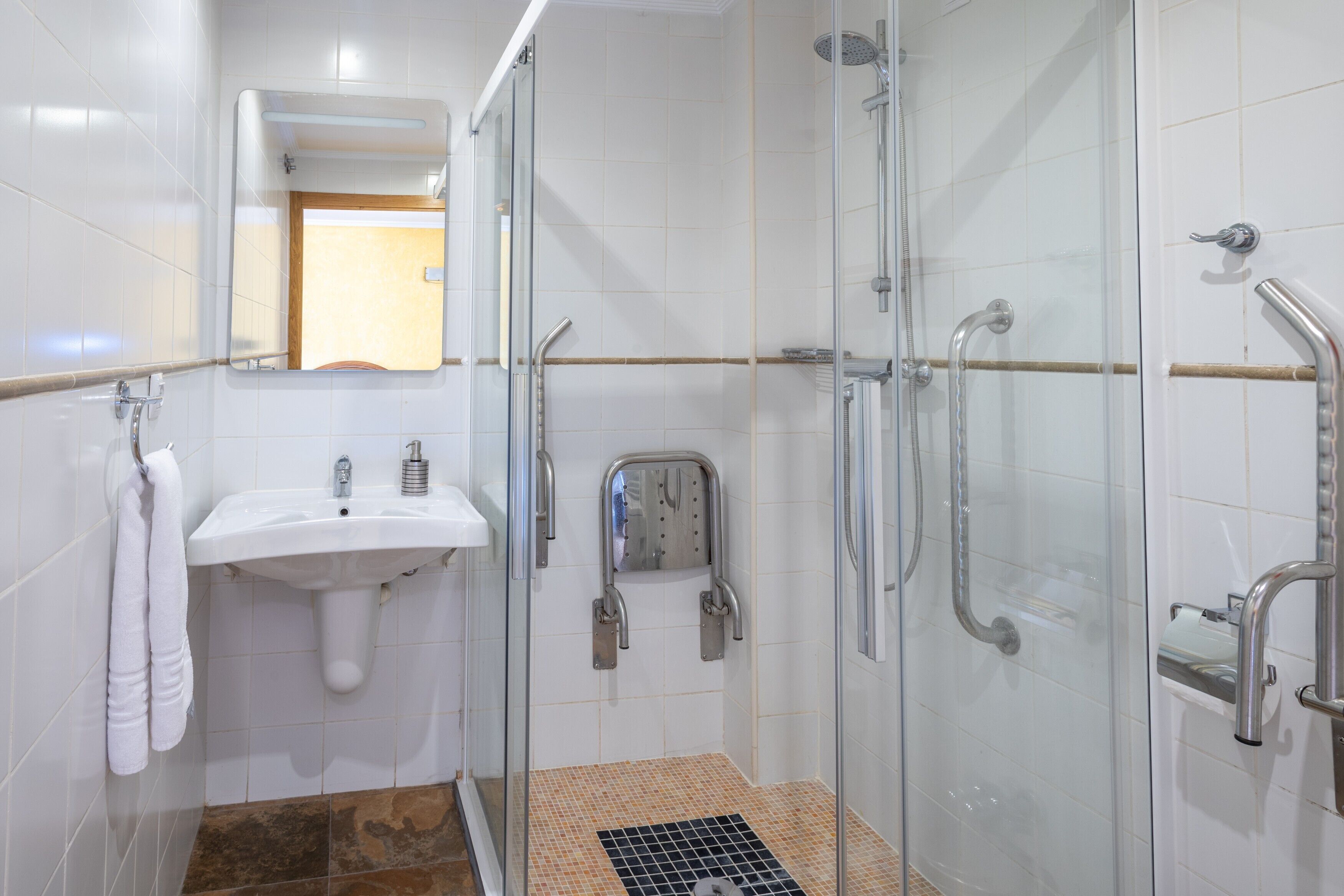 Un baño con ducha de vidrio, un lavamanos y un espejo.