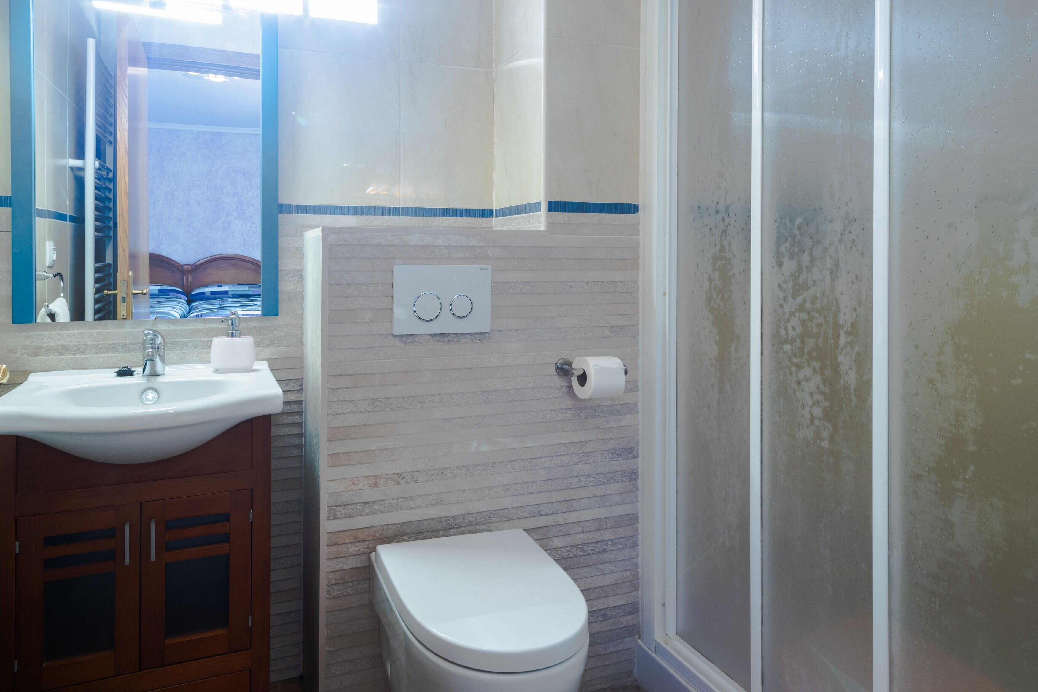 Een badkamer met een wastafel, toilet en spiegel.