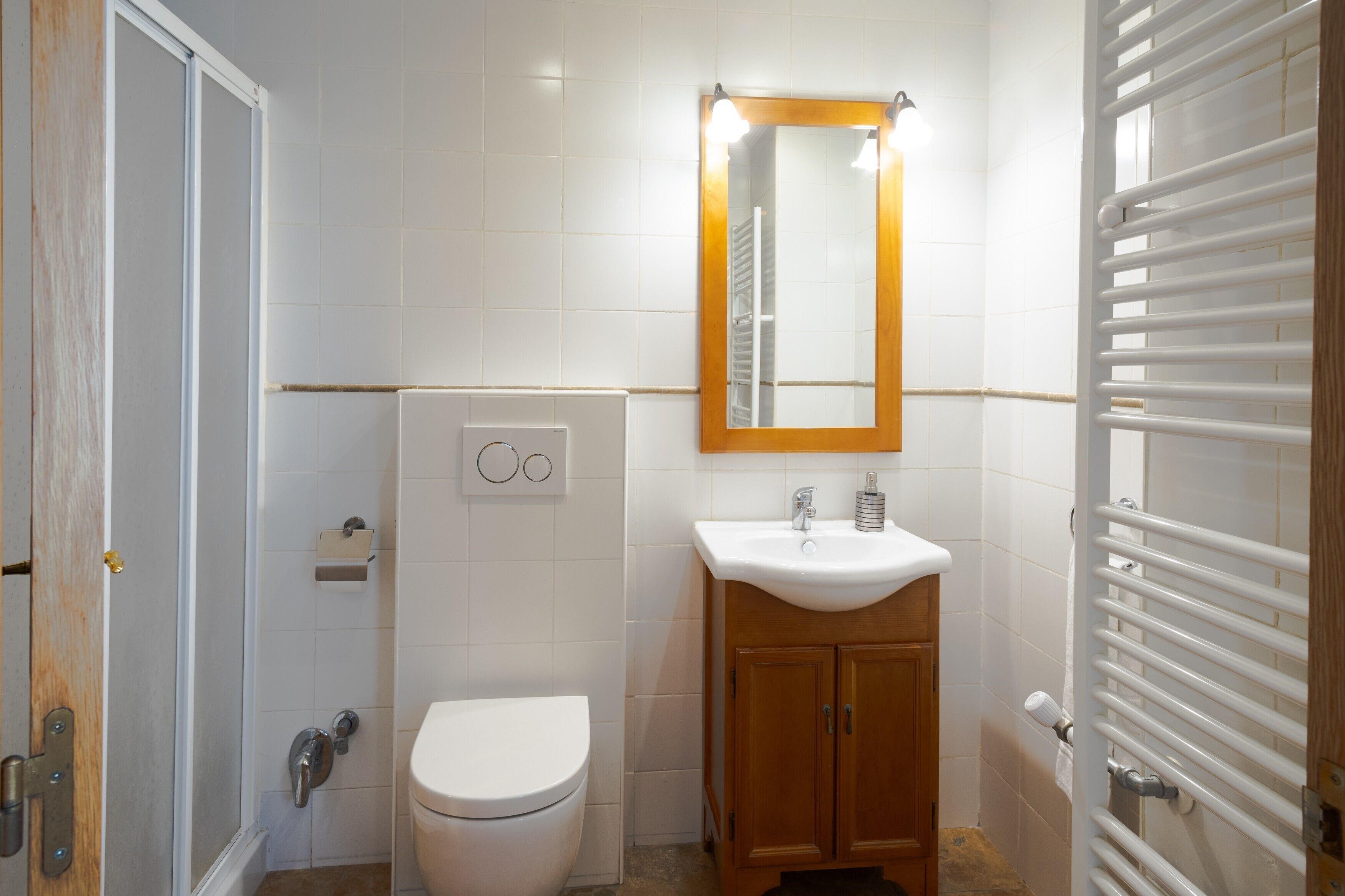 Un baño con inodoro, lavabo, espejo y toallero.