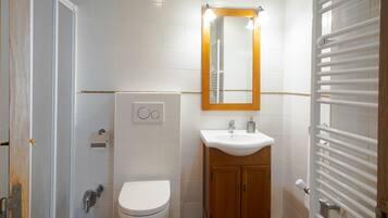 Un baño con inodoro, lavabo, espejo y toallero.