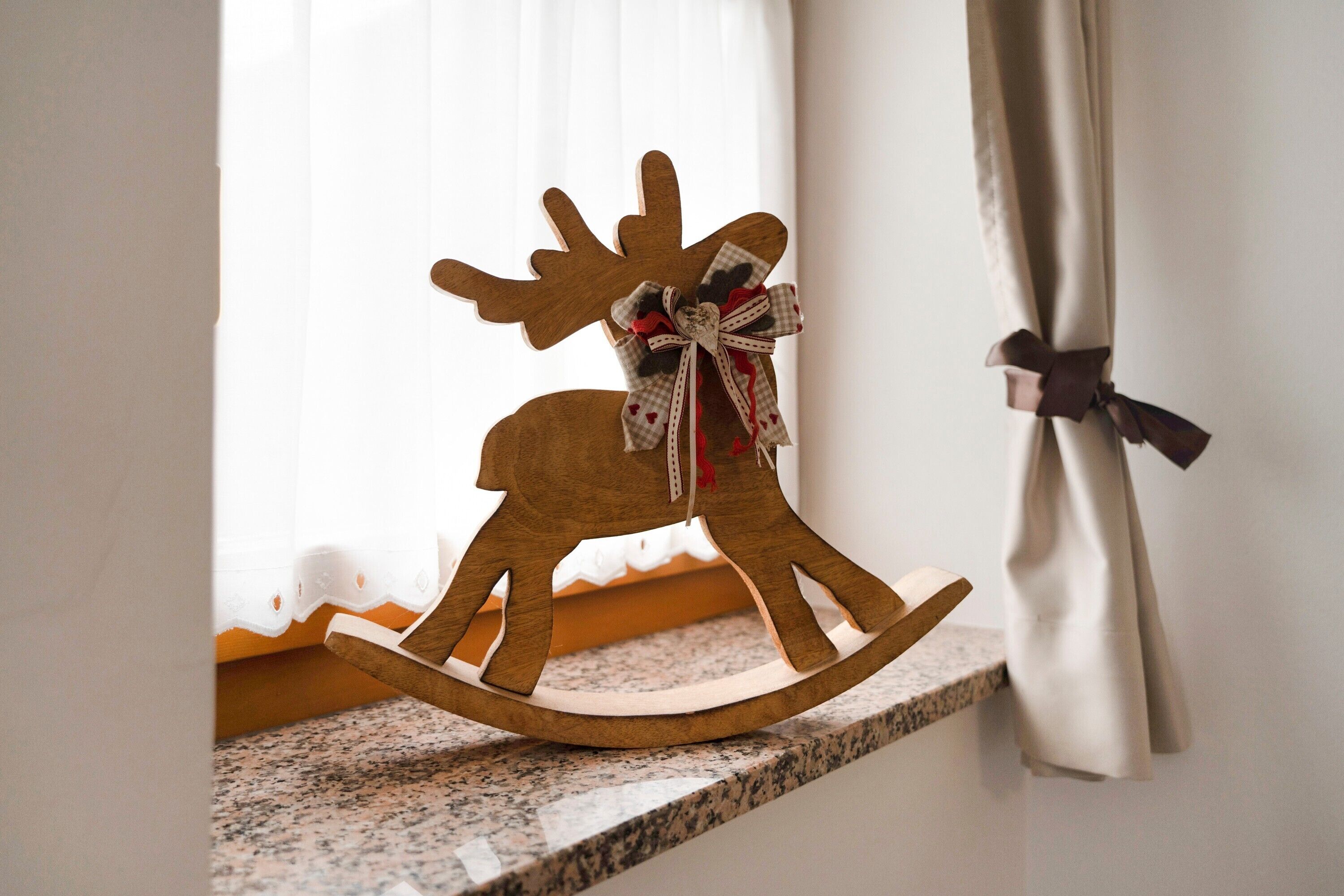 A wooden rocking horse with a bow on a kitchen counter.