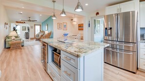 A modern kitchen with stainless steel appliances, a marble countertop, and a dining area with a table and chairs. - Lux Canal Front 4 bedroom - Home w/ Dock, Near Looe Key – Fishing, Diving & Sunsets! (Ramrod Key)