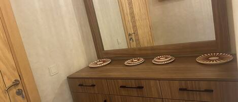 Un meuble en bois orné de quatre assiettes décoratives sur le dessus et d’un miroir qui reflète une porte aux sculptures complexes.