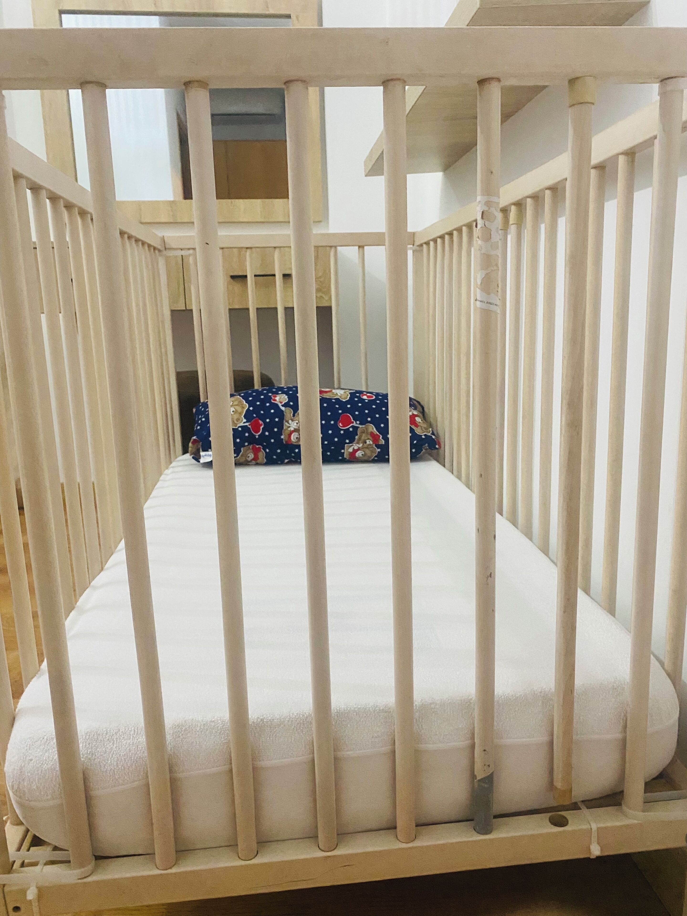 Un berceau avec un matelas blanc et un oreiller bleu à motifs.
