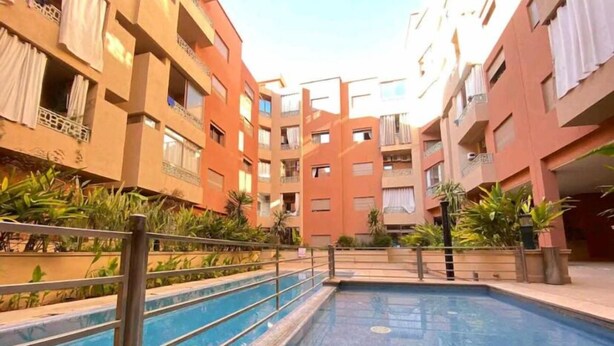 Un immeuble résidentiel doté d’une piscine, de balcons et de plantes en pot.