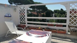 En terrasse med et hvidt bord, stole og plantekrukker.