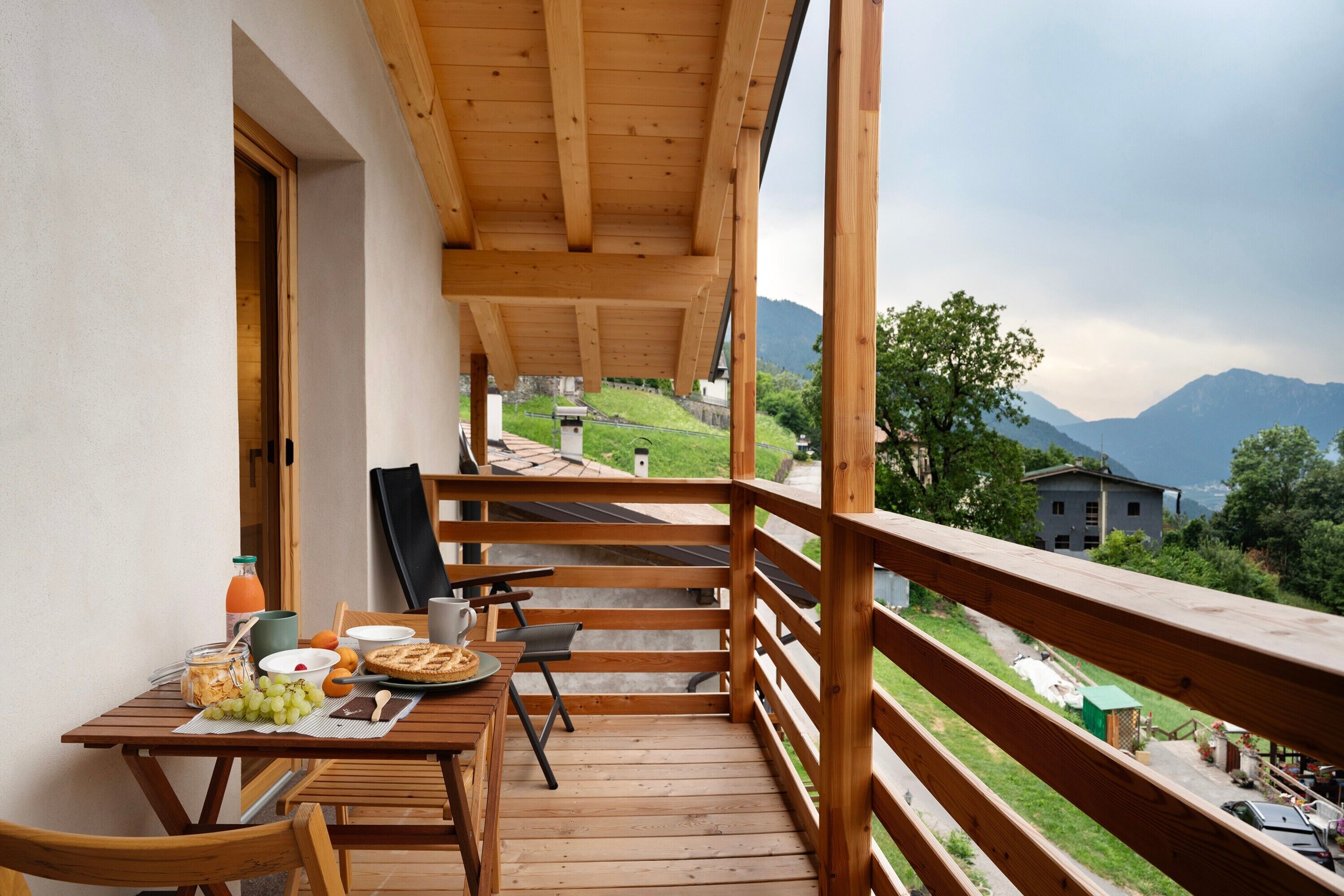 Ein Holzbalkon mit gedecktem Frühstückstisch, mit Blick auf eine Berglandschaft.