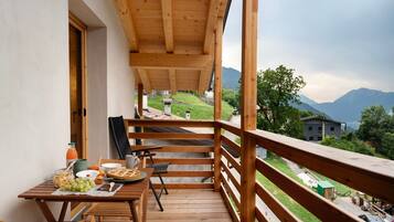 Ein Holzbalkon mit gedecktem Frühstückstisch, mit Blick auf eine Berglandschaft.