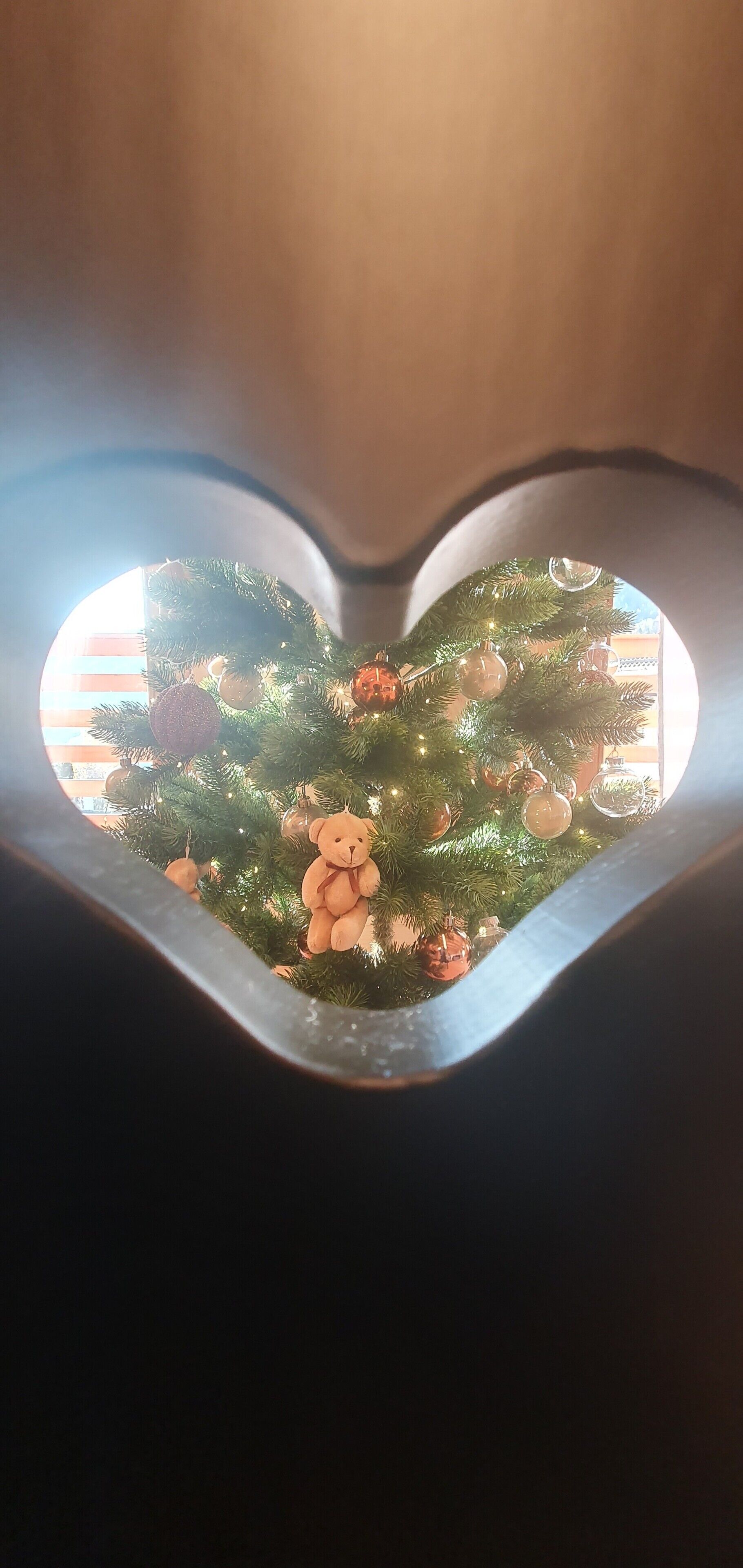 Ein herzförmiges Fenster mit einem Weihnachtsbaum im Inneren.