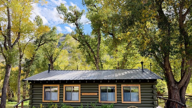 En hyggelig hytte med metal tag, trævinduer og et skilt, der siger "Rural Vista Cabin".