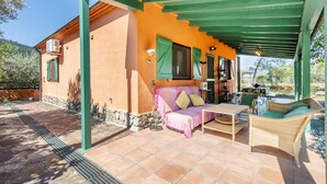 Eine überdachte Terrasse mit einer Couch, Korbmöbeln und einem Tisch.