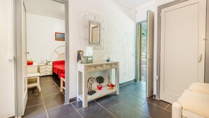 Ein Schlafzimmer mit Bett, Nachttisch, Spiegel und einer Tür zu einem anderen Raum.