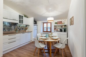 A modern kitchen with white cabinets, a dining table with chairs, and a hanging light fixture. - Apartment 'Il Teatro' with Wi-Fi and Air Conditioning (San Gimignano)