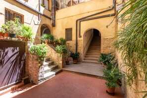 Ein Innenhof mit Treppe, Kübelpflanzen und einer Ziegelwand.