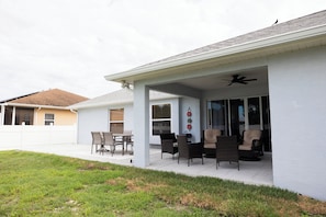 A covered patio area with outdoor furniture, a ceiling fan, and a view of neighboring houses.