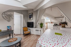 Moderni, avoimen pohjaratkaisun makuuhuone, jossa on suuri sänky, työpöytä, televisio ja ruokailutila.