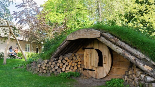 A rustic wooden structure with a thatched roof, surrounded by logs and greenery. - Contemporary Chalet, Near De Efteling (Kaatsheuvel)
