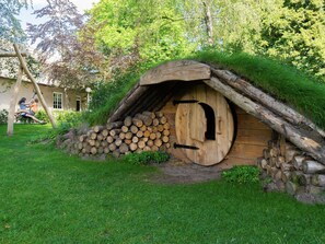 A rustic wooden structure with a thatched roof, surrounded by logs and greenery. - Contemporary Chalet, Near De Efteling (Kaatsheuvel)