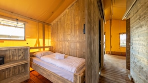 A wooden room with a bed, a small table, and a window. - Charming Safari Tent by the Lake (Gasselternijveen)