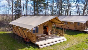 A campsite with two tents, each featuring a porch with a bench and a table. - Charming Safari Tent by the Lake (Gasselternijveen)