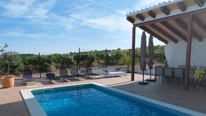A swimming pool with lounge chairs and a pergola.