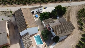 A residential property with multiple buildings, a swimming pool, and a vineyard in the background.