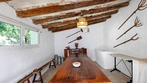 A rustic dining room with a wooden table, benches, and a hanging light fixture.