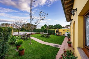 Un jardín bien cuidado con un patio, mobiliario exterior y un sendero que lleva a un edificio.