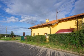 Un edificio amarillo con un toldo rojo, una chimenea y un cartel.