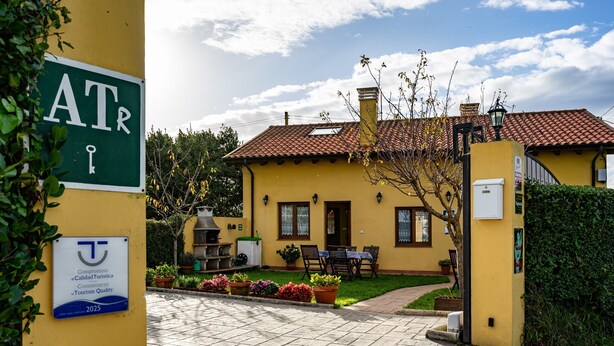 A yellow building with a tiled roof, a patio with outdoor furniture, and a gate. - Country House 'Apartamento Rosa' with Shared Garden (Susacasa)