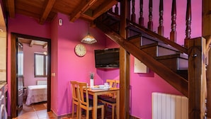 A dining area with wooden chairs and a table, a clock on the wall, and a staircase with wooden railings. - Country House 'Apartamento Rosa' with Shared Garden (Susacasa)