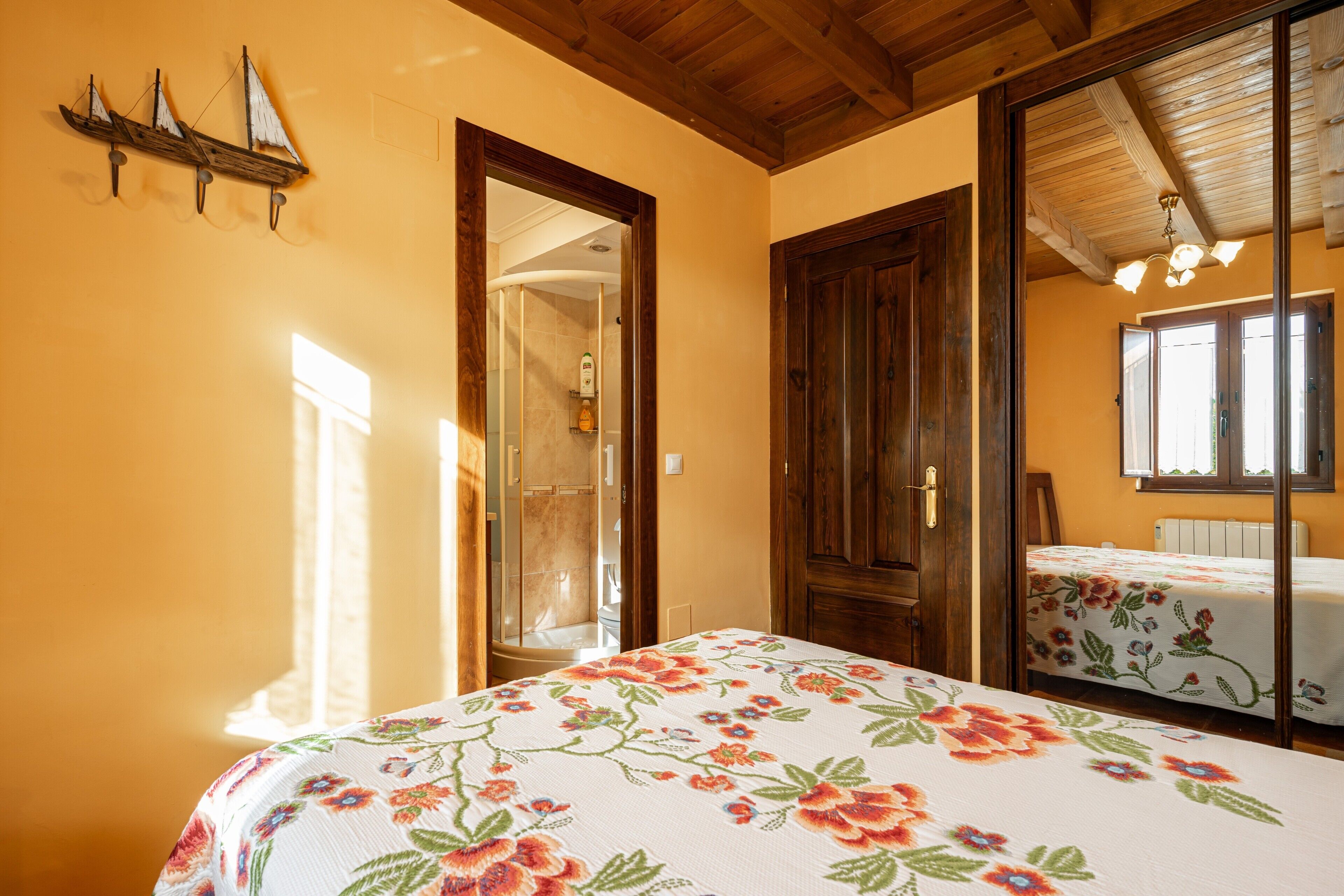 A bedroom with a bed, wooden doors, a mirror, and a window.