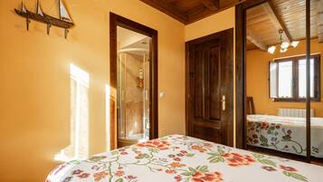 A bedroom with a bed, wooden doors, a mirror, and a window.