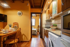 A kitchen with wooden cabinets, a washing machine, and a dining area with chairs and a table.