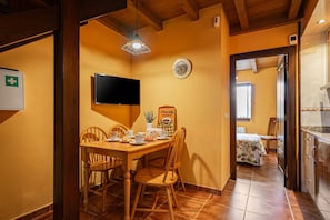 A dining area with a wooden table, chairs, a television, and a clock on the wall.