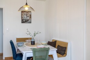 Un área de comedor con una mesa, sillas, un florero con flores, una lámpara colgante y un cuadro en la pared.