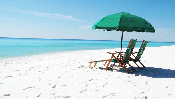 A beach scene with a green umbrella and two wooden beach chairs on a sandy shore. - Gulf Dunes 507 • Amazing Direct Ocean View, 6th Floor Beach Condo, Tennis, Free Beach Service (Fort Walton Beach)