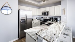 A modern kitchen with white cabinets, stainless steel appliances, and a marble countertop. - Gulf Dunes 507 • Amazing Direct Ocean View, 6th Floor Beach Condo, Tennis, Free Beach Service (Fort Walton Beach)
