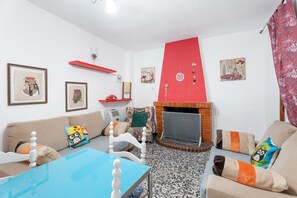 A living room with a fireplace, sofas, a coffee table, and various wall decorations.
