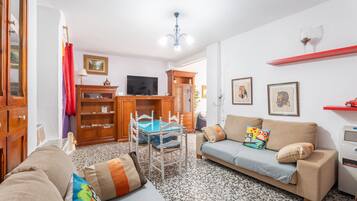 Un salon avec un canapé, un téléviseur, un meuble en bois et un sol à motifs.